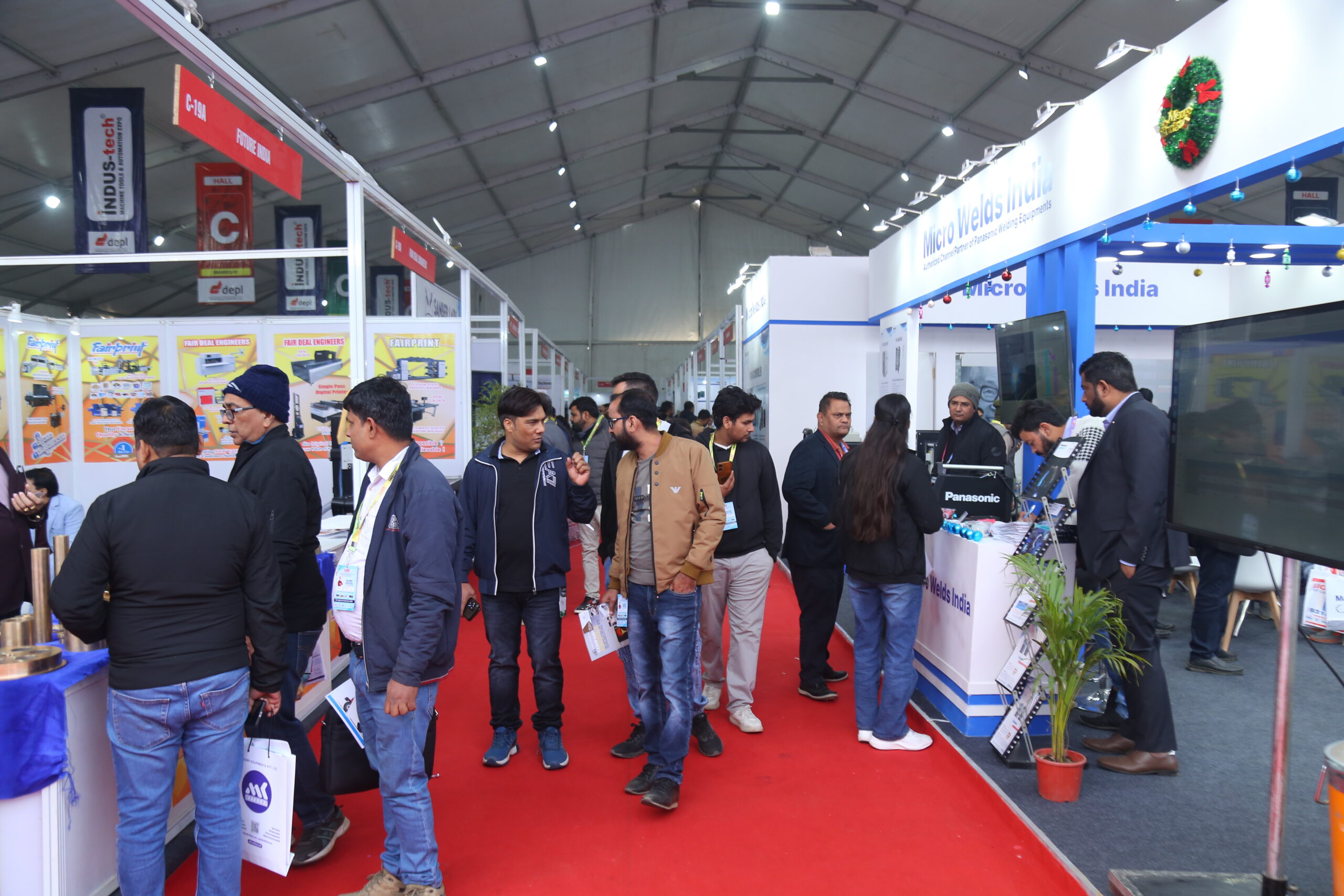 Visitors walking through exhibition hall with Micro Welds India stall